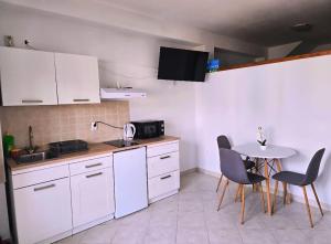 a kitchen with white cabinets and a table and chairs at Apartmani Ante 1 in Drašnice