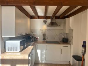 a kitchen with white cabinets and a microwave at Le Cantilien Apartment - Chantilly in Chantilly