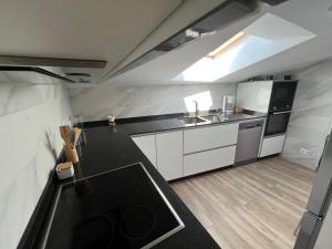a kitchen with white cabinets and a black counter top at Ático en pleno centro en Cangas in Cangas de Morrazo