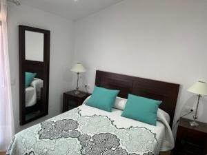 a bedroom with a bed with blue pillows and a mirror at Ático en pleno centro en Cangas in Cangas de Morrazo