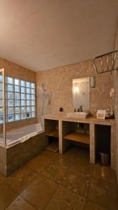 a bathroom with a tub and a sink and a mirror at Hôtel la Fête en Provence in Vaison-la-Romaine +97 photos