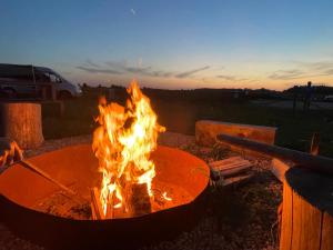 a fire pit with flames in it at dusk at Weź Wyjdź - Podlaski Glamping in Łazy