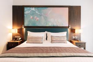a bedroom with a bed with a painting above it at The Lodge Hotel in Coleraine +74 photos