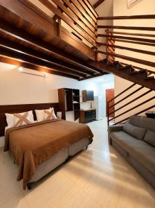 a bedroom with a large bed and a couch at NaPraia Brasil Pousada in São Miguel do Gostoso