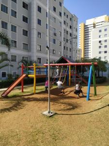 three children playing on a playground in a park at Cantinho aconchegante in Londrina