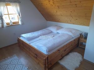 a large wooden bed in a room with a window at Chata pod Urbanovym Vrchom in Čierny Blh