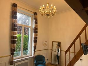 a staircase with a chandelier and a chair next to a window at Le Cantilien Apartment - Chantilly in Chantilly