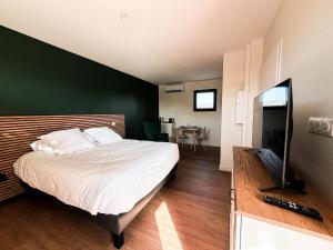 a bedroom with a large bed with a green wall at Claïla Appart-Hôtel Abzac in Abzac