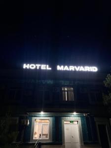 a hotel manager sign on top of a building at night at Marvarid Hotel in Ghijduwon
