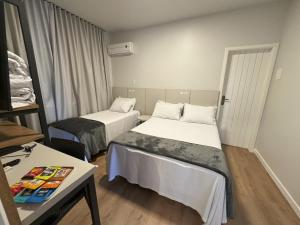 a hotel room with two beds and a table at Rio Jordao Hotel in Siderópolis