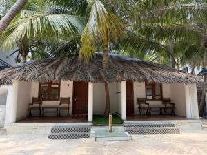 a small hut with a straw roof with a palm tree at PP Beach Villa in Agatti