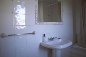 a white bathroom with a sink and a mirror at Casa Pousadoira in Miño