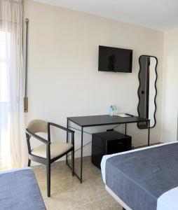 a room with a desk and a chair and a television at STAR BAY Hotel in Calafell