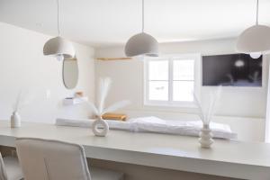 a white kitchen with a table with chairs and pendant lights at Nama Suites in Skopelos Town