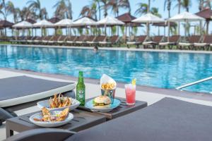 a table with food and drinks next to a swimming pool at Vila Galé Collection Sunset Cumbuco in Cumbuco