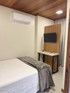 a bedroom with a bed and a desk with a tv at Rio Jordao Hotel in Siderópolis