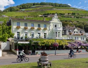 due persone in bicicletta lungo una strada di fronte a un edificio di Hotel Schön am Rhein a Rüdesheim am Rhein