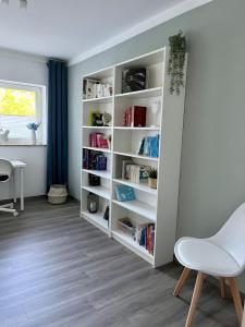 a white book shelf in a room with a chair at Ferienwohnung Schöpf - Fränkische Schweiz in Obertrubach