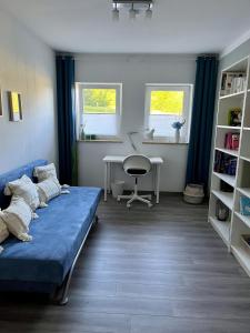 a living room with a blue couch and a desk at Ferienwohnung Schöpf - Fränkische Schweiz in Obertrubach