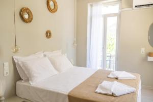 a white bedroom with a bed with two towels on it at Nama Suites in Skopelos Town