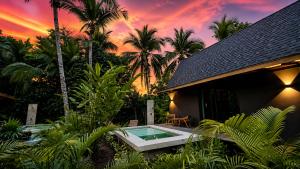 a house with a swimming pool in front of a sunset at Namu Garden Hotel & Spa - Adults Only in Puerto Viejo