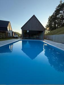 a swimming pool with blue water in front of a building at Aura Kaszub Lake&Forest in Łączyno
