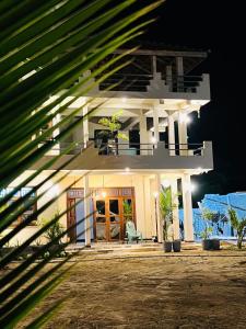a large white house with a porch at night at Luna Mara in Arugam Bay