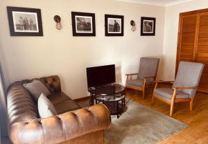 a living room with a leather couch and two chairs at Inn at Port nan Gael in Pennyghael