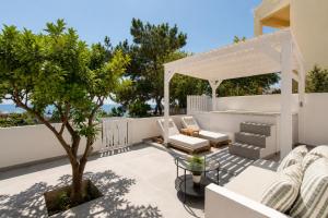 a patio with a white pergola and a tree at Theros Luxury Apartment in Archangelos