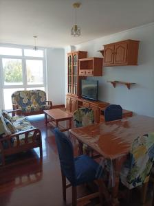 a living room with a table and chairs and a tv at Refugio Mar de Boiro in Boiro