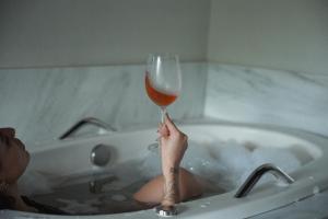 a person sitting in a bath tub holding a glass of wine at Refúgio do Cacupé in Florianópolis