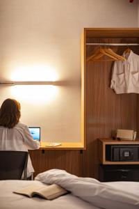 a woman sitting at a desk with a laptop in a room at Moov Hotel São Paulo in São Paulo