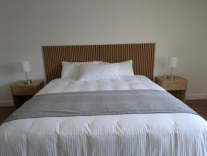 a large bed with two nightstands and two lamps at Auberge des 21 in La Baie