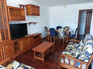 a living room with a tv and a couch and a table at Refugio Mar de Boiro in Boiro