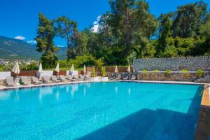 a large swimming pool with lounge chairs and umbrellas at Casa De Levıssı Ölüdeniz in Oludeniz