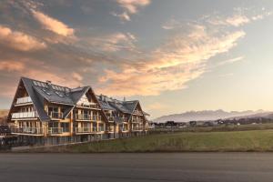 a large building with a roof on a field at Apartament Stary Drewniany Białka Ski Resort -obok Termy Bania i Kotelnica in Białka Tatrzańska