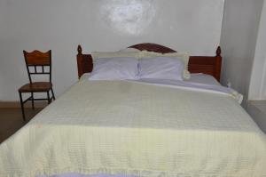 a bed with a yellow and white comforter and a chair at Brabus Appartment Motel in Rubavu