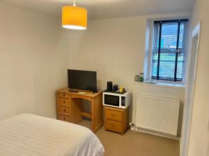 a bedroom with a bed and a desk with a television at The Bognie Inn in Huntly