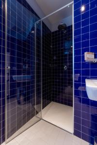 a blue tiled bathroom with a shower and a sink at Hotel Valeria in Villa Opicina