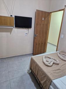 a room with a bed and a television and a door at Pousada Mar de Pajuçara in Maceió