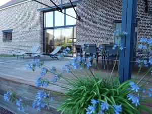 a wooden deck with blue flowers in front of a brick building at La Grange in Chérisy