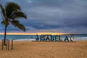 a sign on a beach with a palm tree at Hospedaje Isabela in Puerto Villamil +1 photo