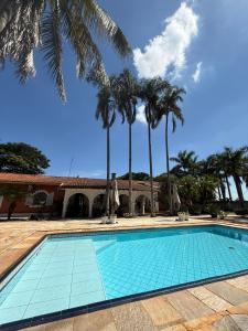 a swimming pool with palm trees in front of a building at VILLA ARATOCA in Garça