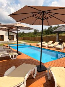 a swimming pool with lounge chairs and an umbrella at Братановите Къщи in Dŭbravka