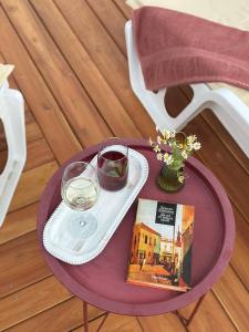 a purple table with a glass of wine and a book at Братановите Къщи in Dŭbravka
