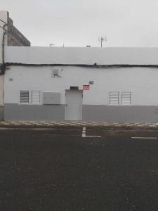 a large white building with two doors and a street at Alojamiento MEL BEACH in Arinaga