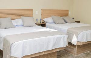 zwei Betten mit weißen Laken in einem Zimmer in der Unterkunft Hotel & Suites JM in Orizatlán