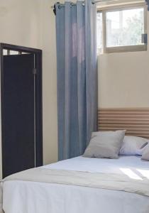 ein Schlafzimmer mit einem Bett, blauen Vorhängen und einem Fenster in der Unterkunft Hotel & Suites JM in Orizatlán