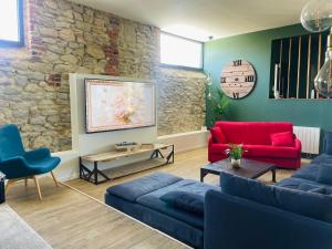 a living room with red furniture and a stone wall at Gîte grand confort 15 personnes - Le Domaine - Wimereux in Wimereux