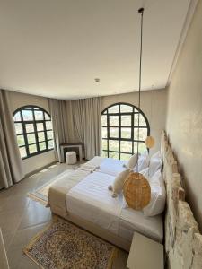 a bedroom with a large bed with two windows at HoneyPath Ocean Retreat in Tamraght Ouzdar